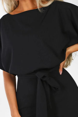 woman wearing a chic short-sleeved wide-leg black jumpsuit with a tied waist belt
