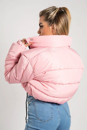 Woman wearing light pink cropped puffer jacket with high collar and zipper detail