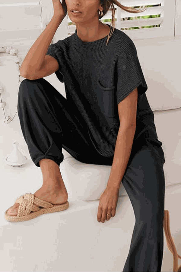 Woman wearing black Comfy Couture Knit Sweater two-piece set with knit pullover and high-waisted pants sitting indoors