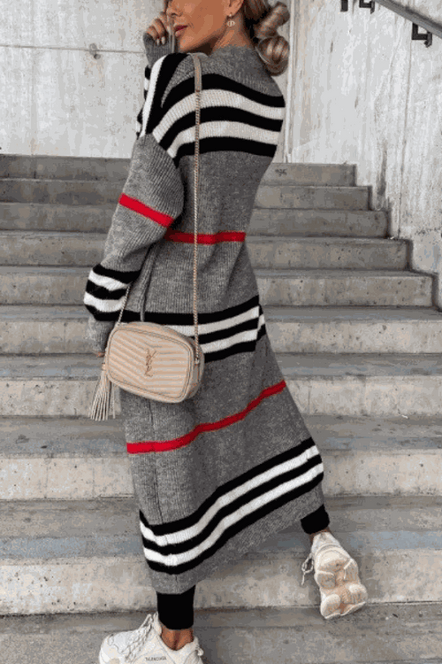 Cozy striped long knitted cardigan with oversized fit and red, black, and white stripes worn by woman on stairs