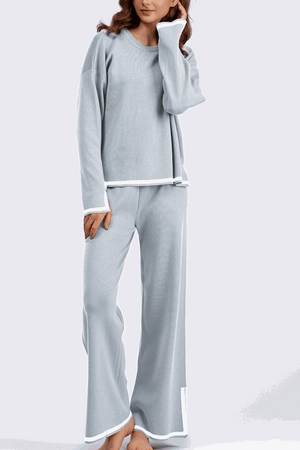 Long sleeved relaxed fit lounge two-piece set in light blue with white trim, featuring a loose sweater and wide-leg palazzo pants.