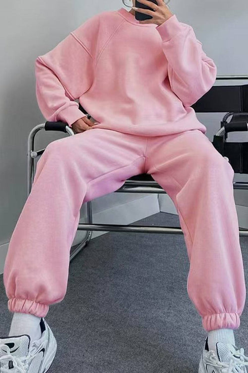Pink comfy chic tracksuit with relaxed fit, long sleeves, and elastic cuffs, paired with white sneakers.