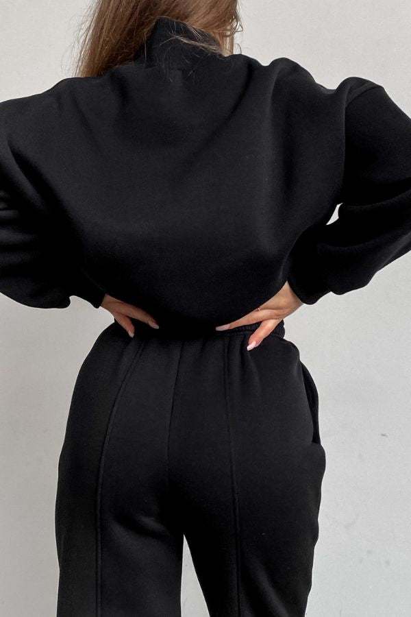 Back view of woman wearing black Storm Sweater Mock Neck athleisure set with relaxed fit and adjustable waist.