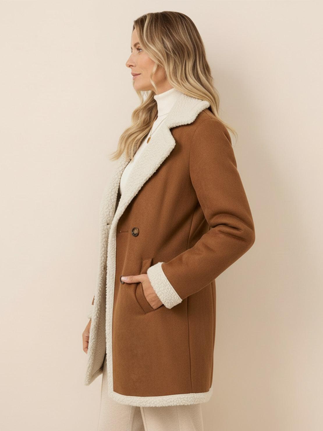 Woman wearing mid-thigh faux suede sherpa coat with contrast collar and side pockets
