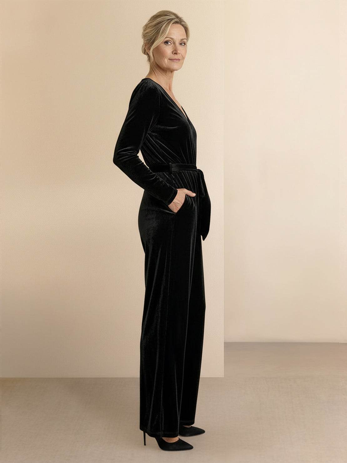 Woman wearing a deep V-neck velvet suit with long sleeves, removable waist tie, and wide-leg pants.