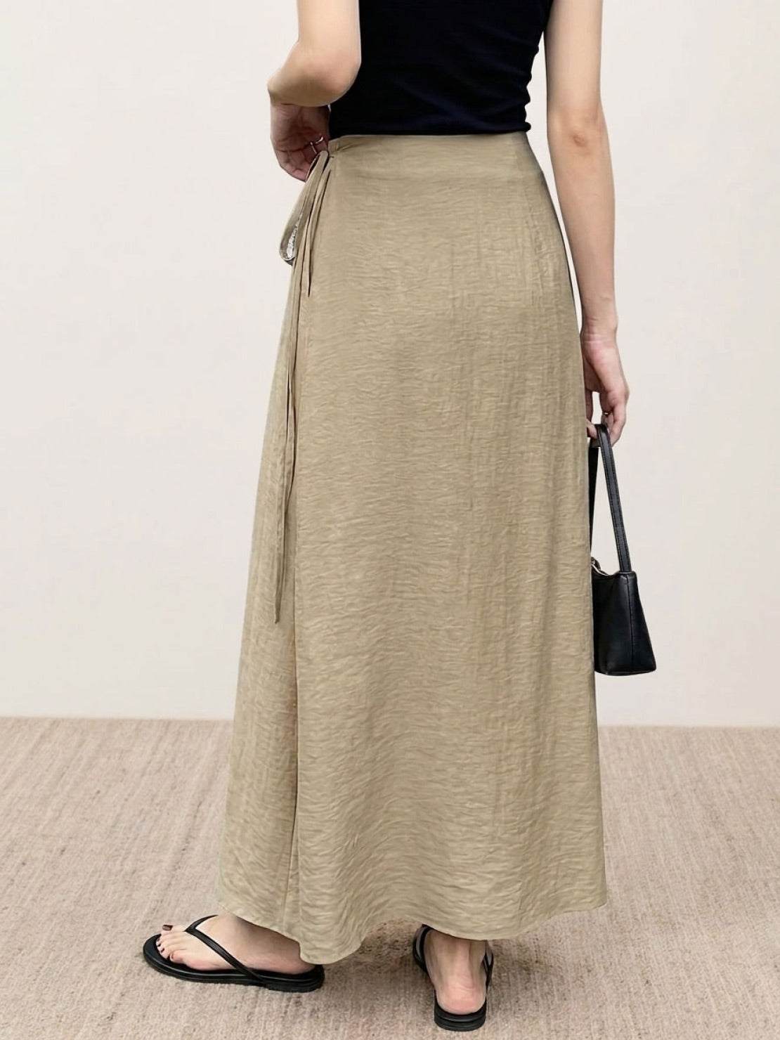 Woman wearing asymmetrical wrap maxi skirt with side tie closure and flowing hem