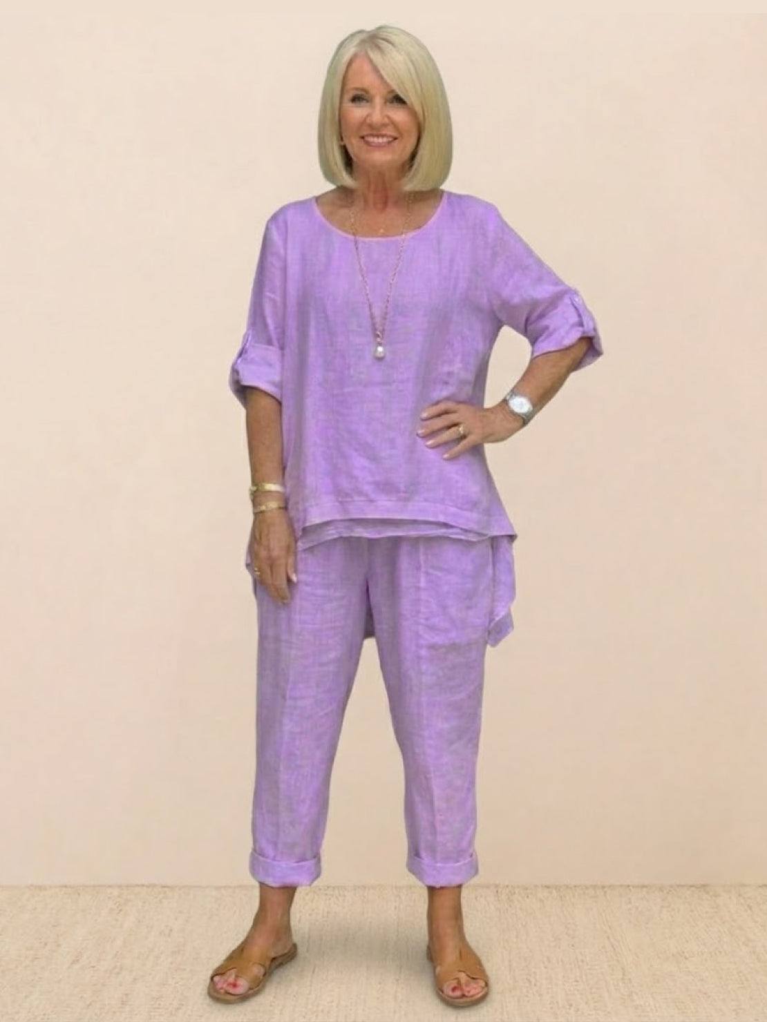 Woman wearing lavender asymmetrical two-piece trouser set with rolled sleeves and tapered pants