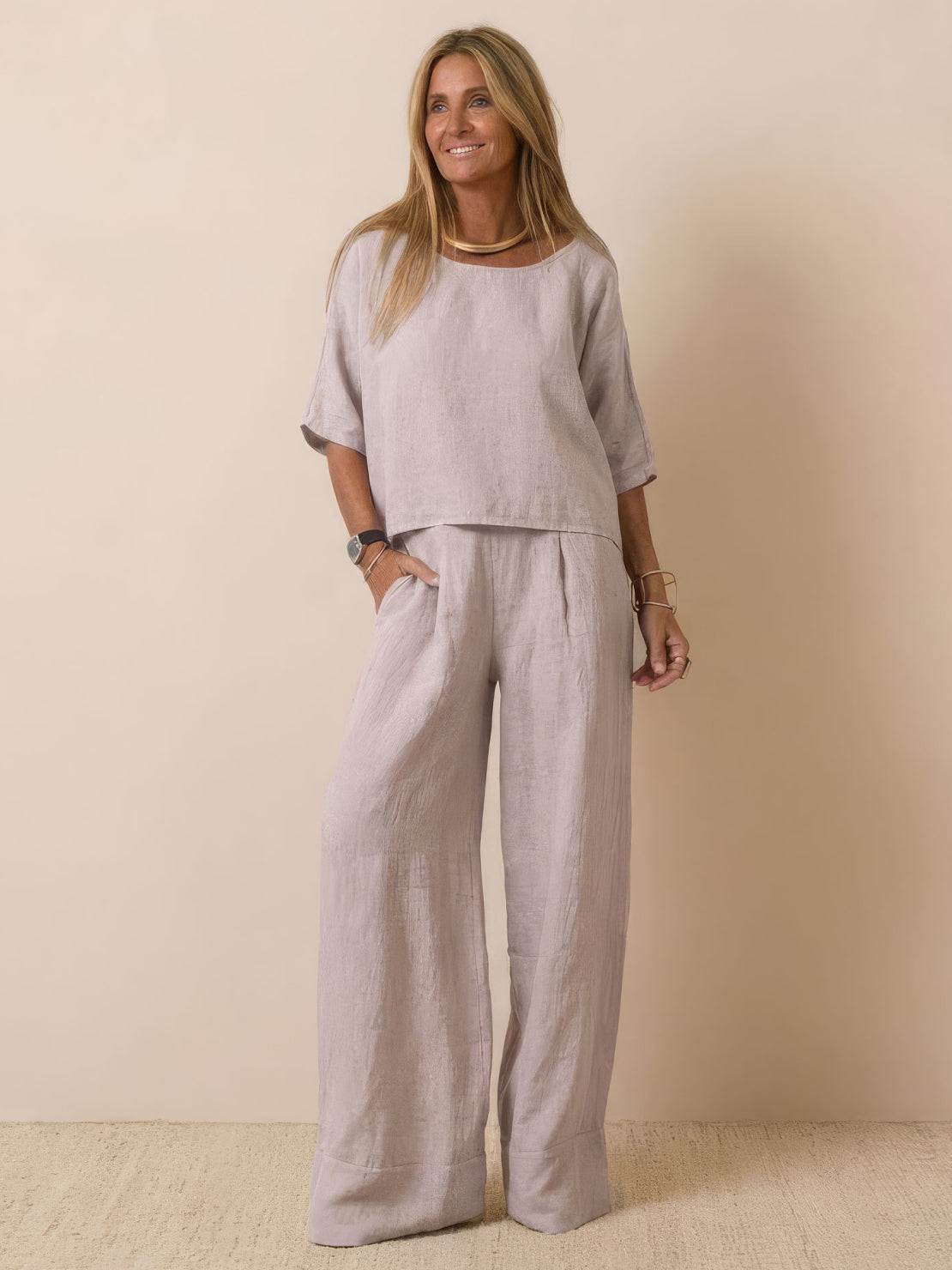 Woman wearing a beige short-sleeved pullover and wide trouser matching set in lightweight cotton fabric.