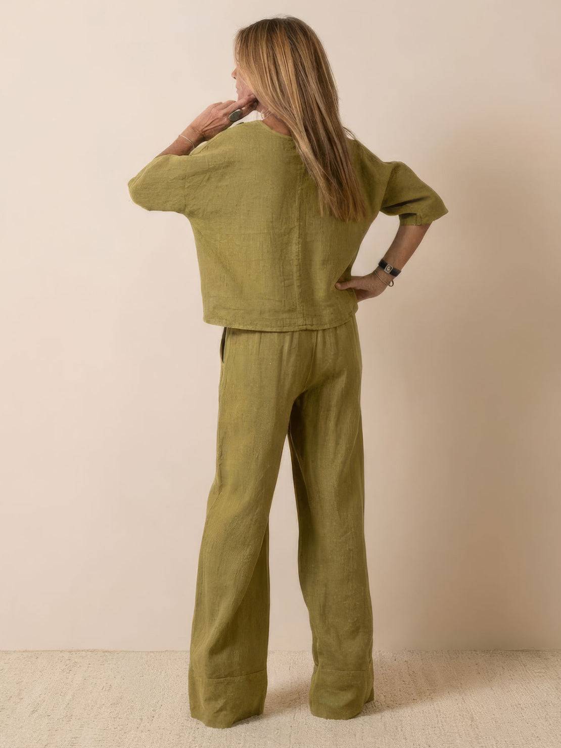 Woman wearing olive green short-sleeved pullover and wide trouser matching set, back view