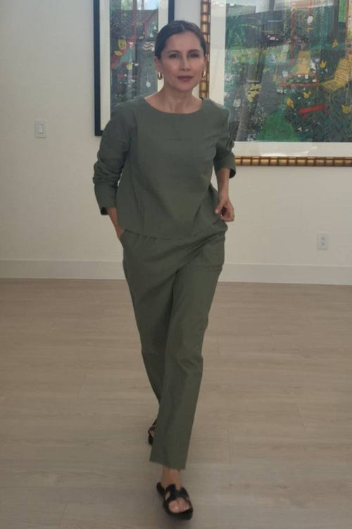 Woman wearing cotton-linen monochrome relaxed longline top and fluid wide-leg pants in muted green indoors