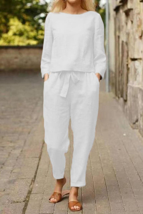Woman wearing white cotton-linen monochrome relaxed longline top and wide-leg pants with brown sandals outdoors