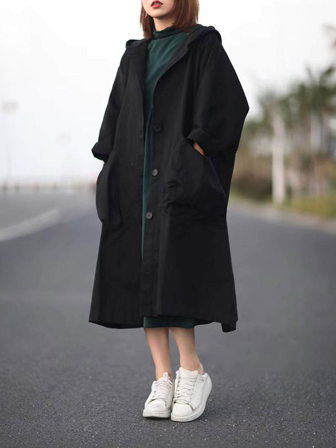 Oversized black water-resistant windbreaker jacket with attached hood and large front pockets, lightweight and longline design