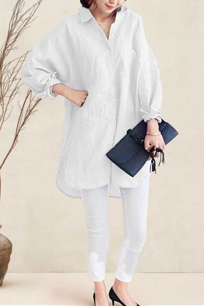 Woman wearing oversized white linen shirt with rolled-up sleeves and holding a black clutch bag