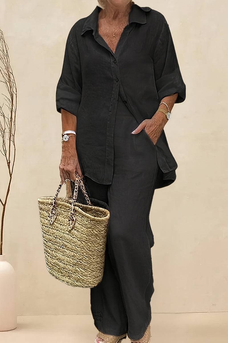Woman wearing oversized 100% cotton black shirt with wide-leg pants co-ord set holding a woven handbag