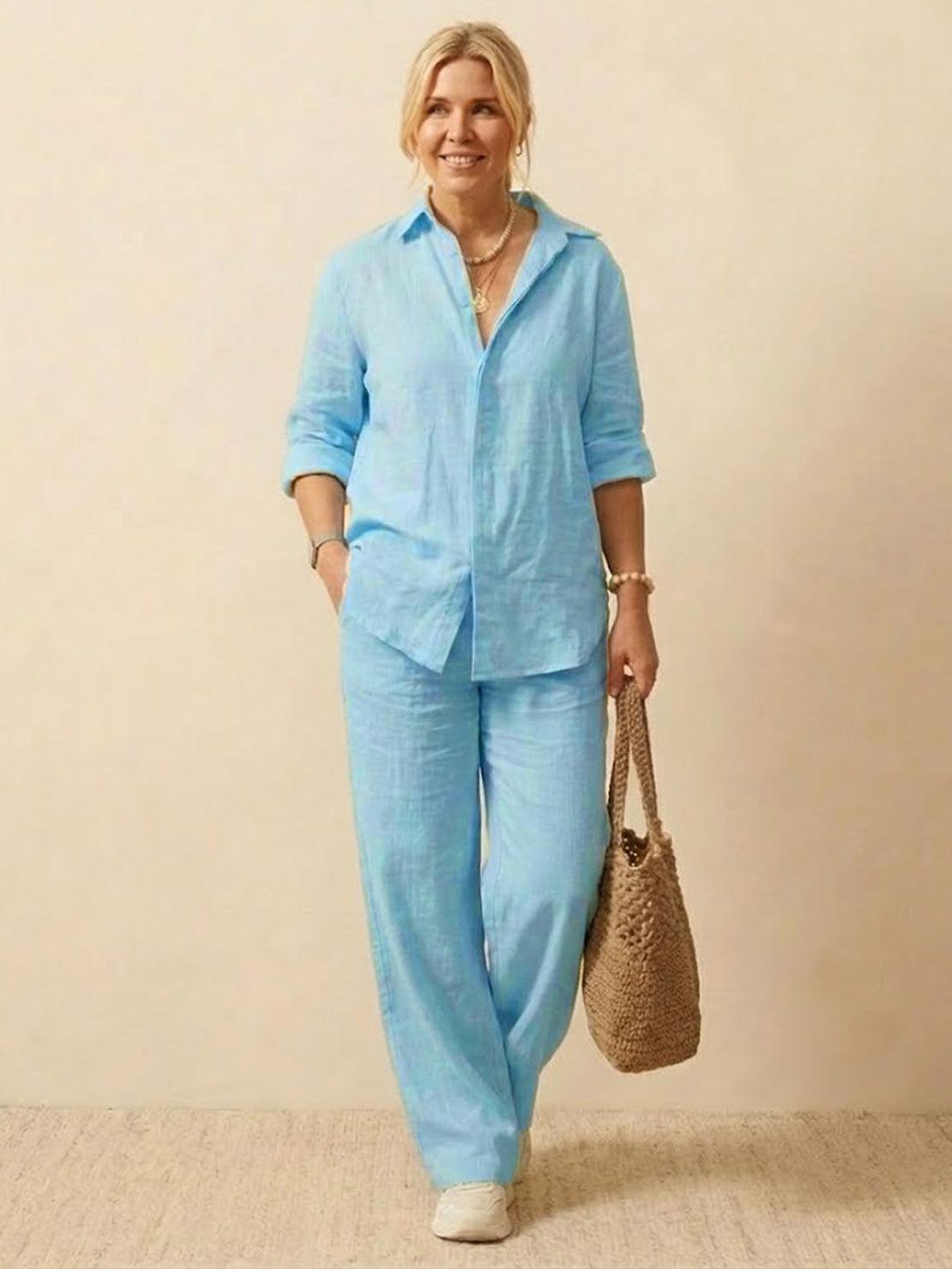 Woman wearing light blue oversized 100% cotton shirt and wide-leg pants co-ord set carrying a woven bag.