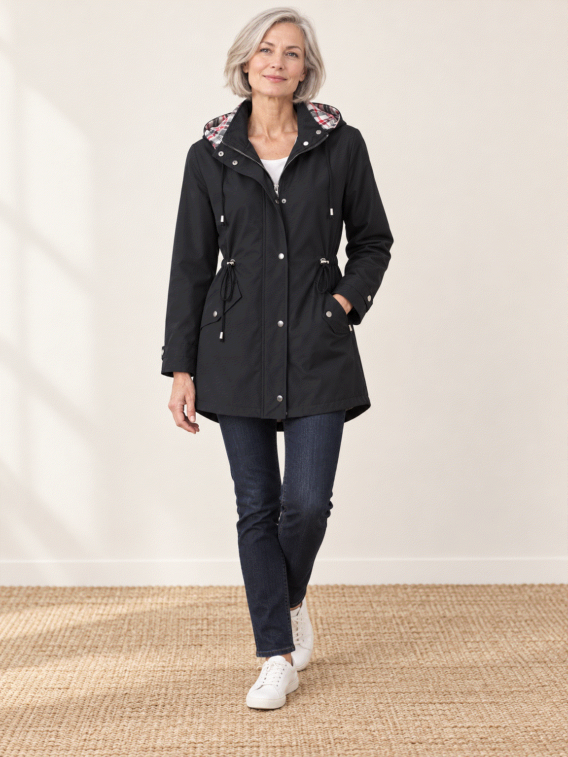 woman wearing plaid-lined hooded rain jacket with tartan interior and drawstring waist outdoors