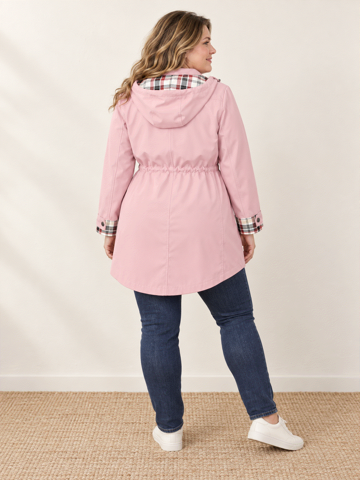 woman wearing plaid-lined hooded rain jacket with waterproof shell and drawstring waist outdoors