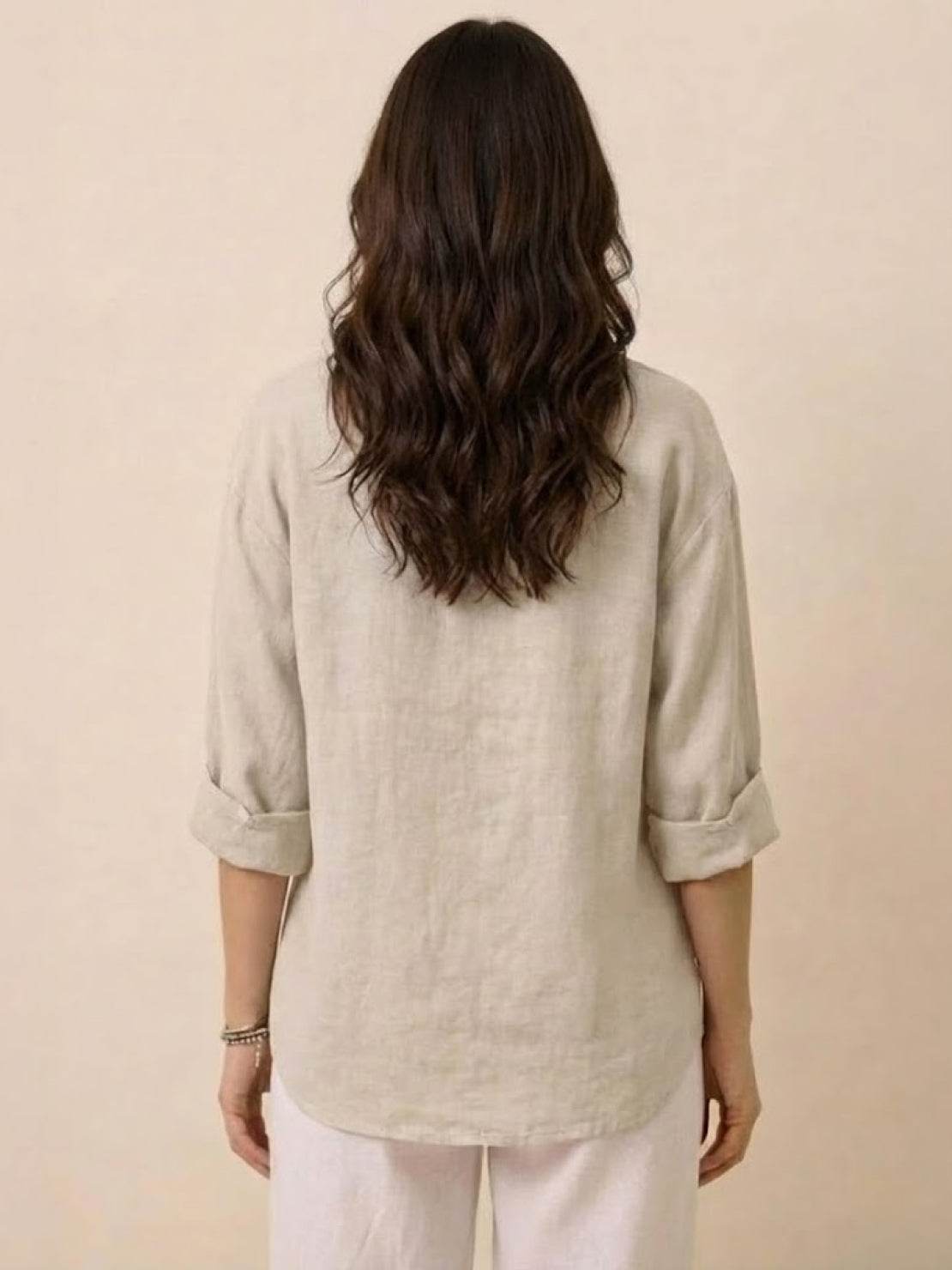 Back view of a woman wearing a beige pure linen age-defying shirt with rolled-up sleeves