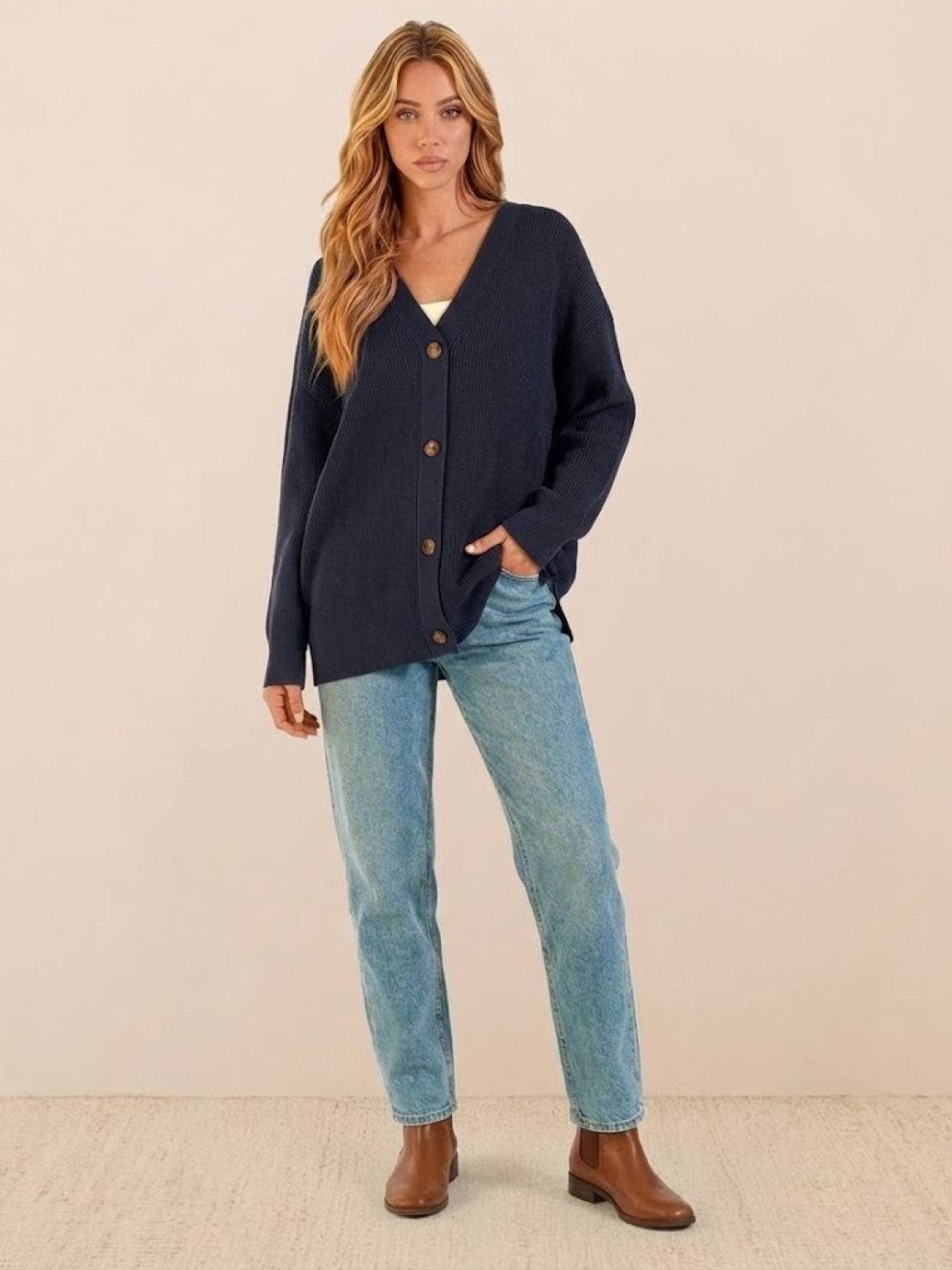 relaxed fit oversized navy blue knit cardigan with buttons worn by woman with jeans and brown boots