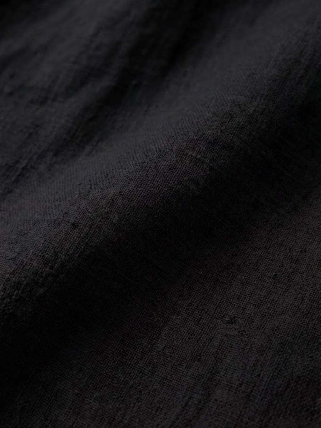 Close-up of black relaxed loose breathable linen fabric texture