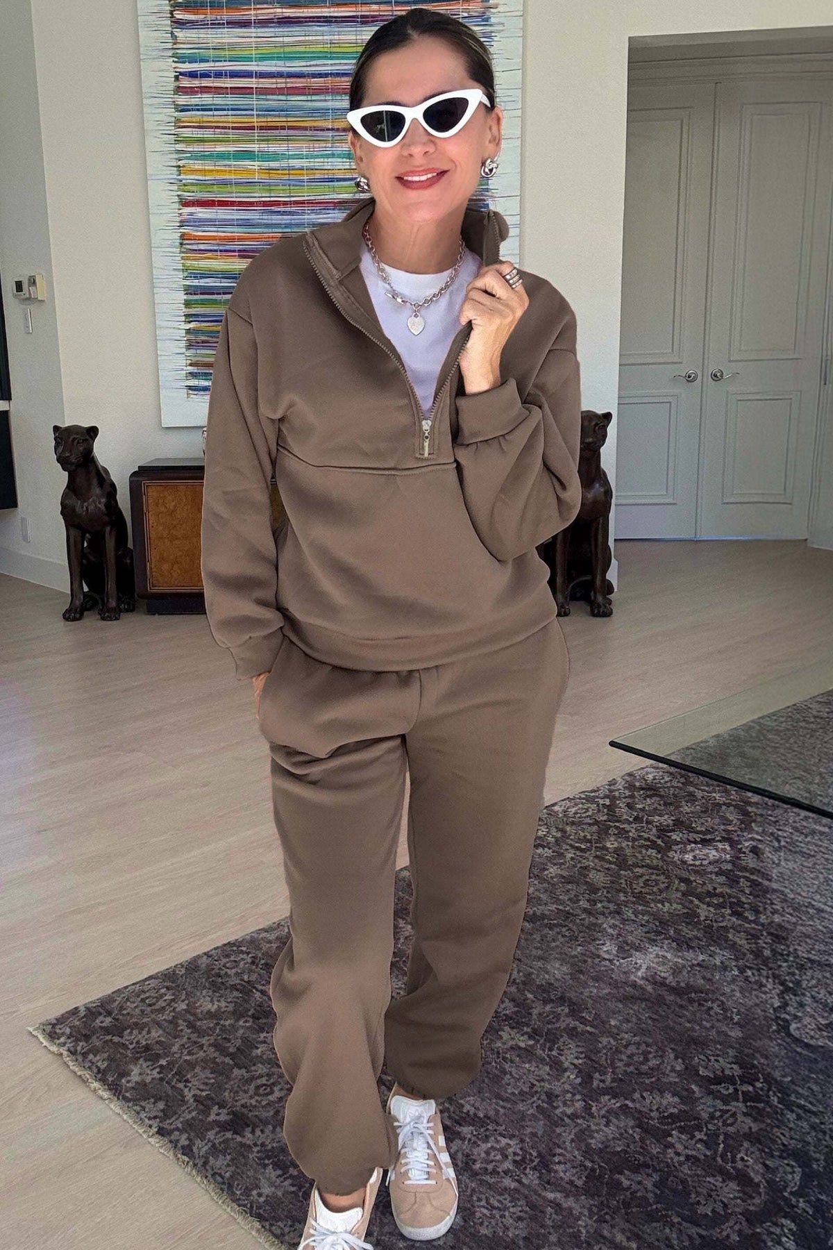 Woman wearing a brown cotton blend tracksuit with a half-zip pullover and matching pants indoors