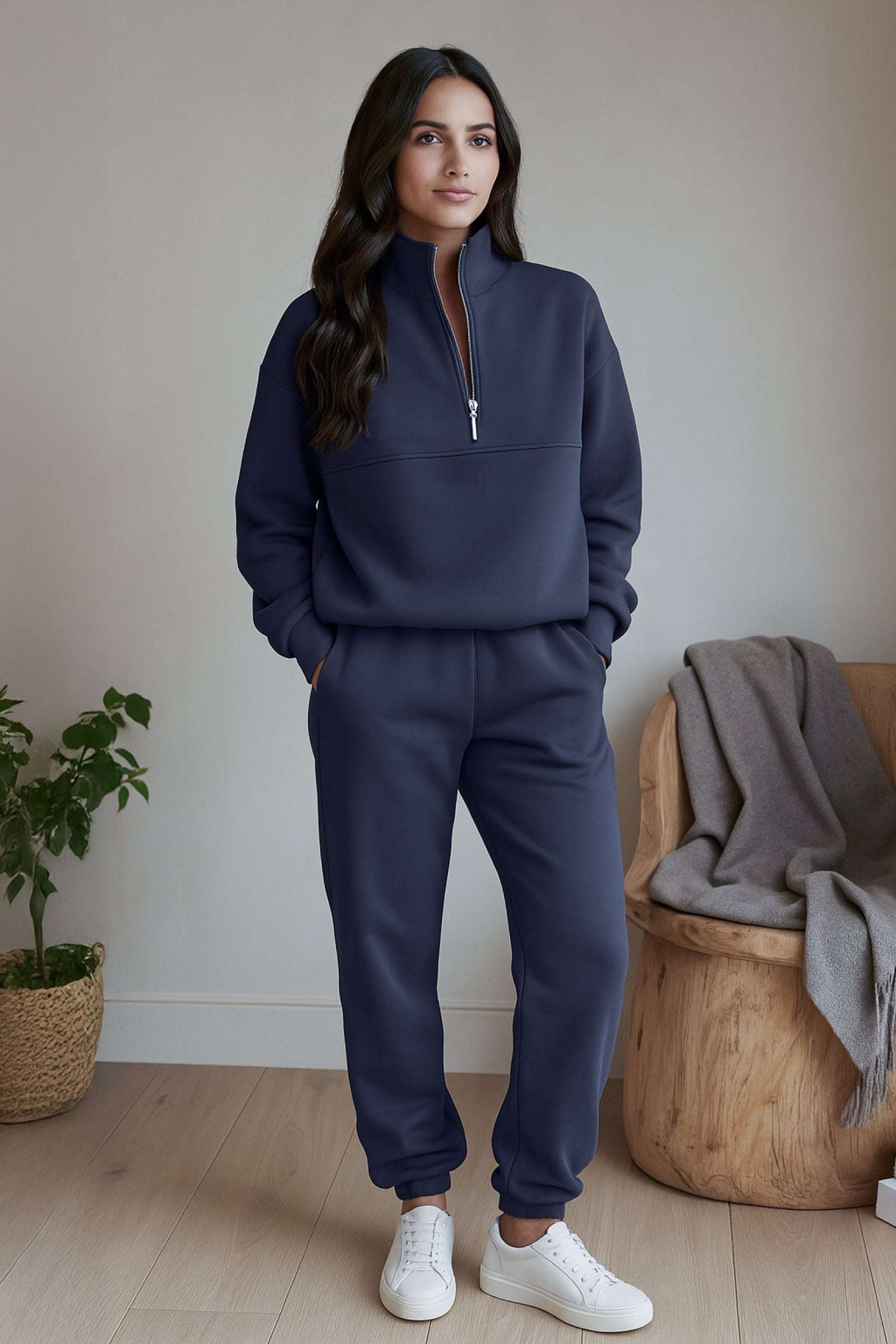 Woman wearing navy cotton blend tracksuit with zip neckline and white sneakers indoors