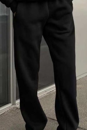 Black cotton blend tracksuit pants with a relaxed fit and stretch waistband worn outdoors