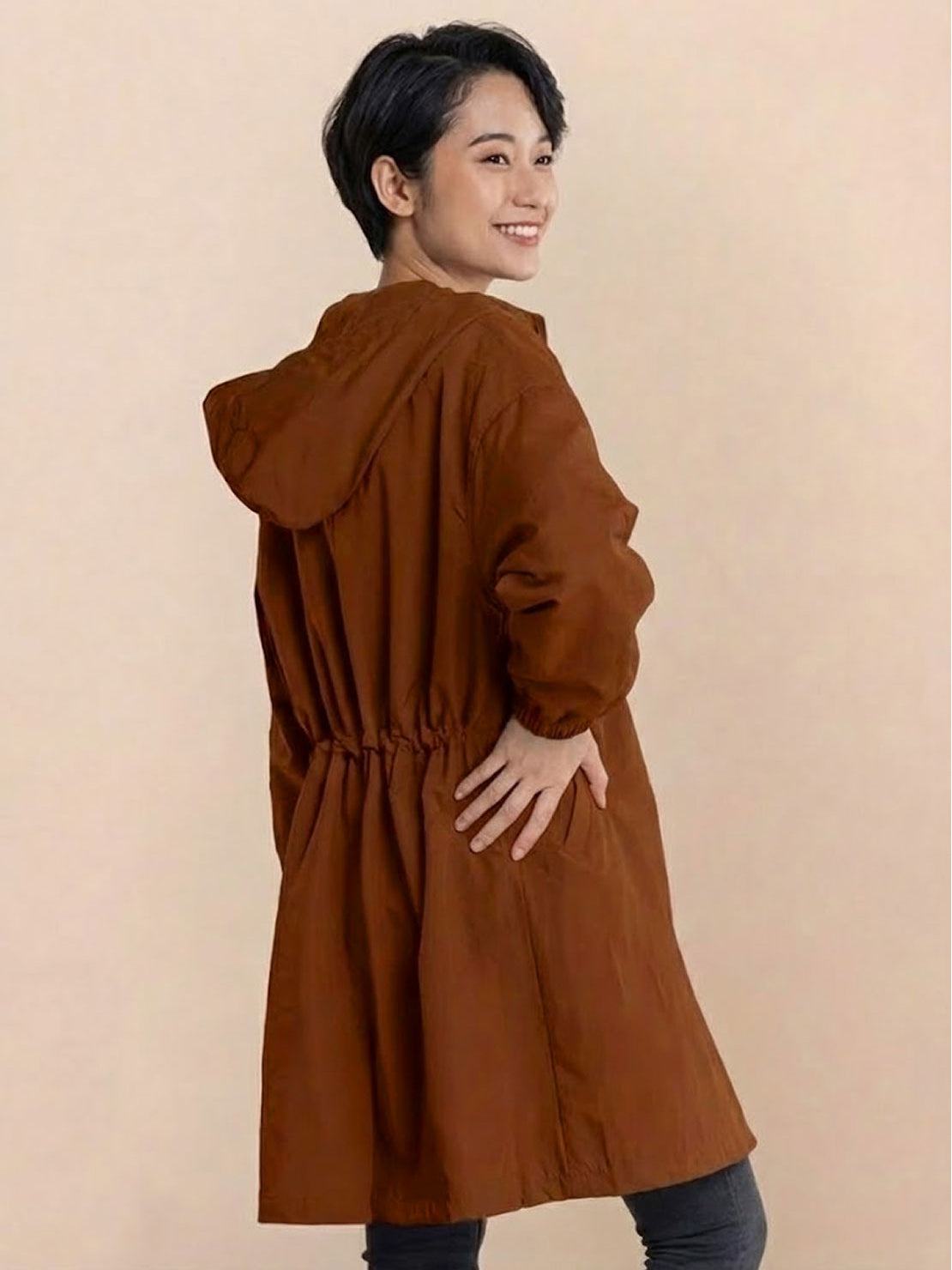 Woman wearing brown oversized Rain Couture Windbreaker with hood and cinched waist back view