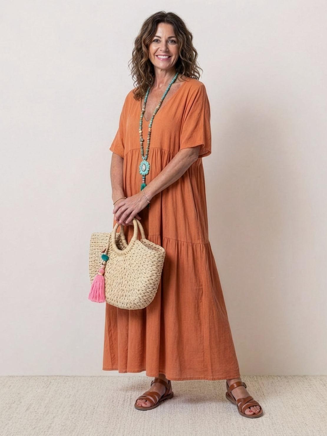 Woman wearing a V-neck two-tiered maxi swing dress with flowing tiers and irregular hemline in solid color