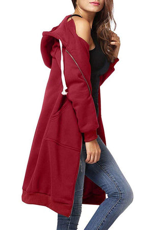 Woman wearing oversized long zip sweatshirt hoodie in red with front pockets and drawstring hood