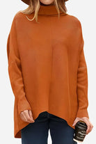 Cozy oversized knit pullover in burnt orange with turtleneck and loose fit style, worn with dark jeans.