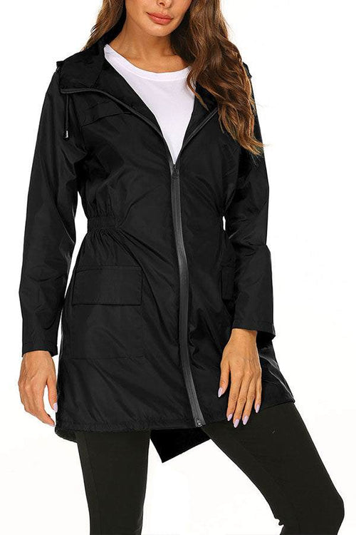 Outdoor and Travel Hooded Raincoat in black lightweight waterproof fabric with front zipper and pockets, worn by woman for travel and outdoor activities