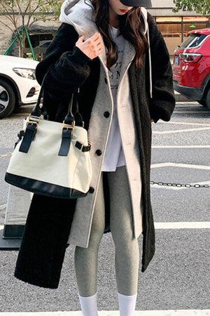 Woman wearing everyday wear oversized sherpa long coat with cozy lining and casual outfit carrying a white and black handbag outdoors