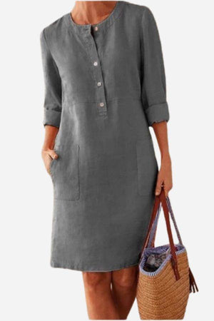 Gray cotton dress with rolled 3/4 sleeves and front buttons, knee-length, styled with woven handbag