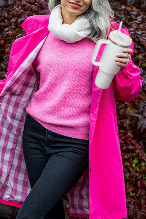 Woman holding indestructible travel cup with lid and straw, wearing pink sweater and jacket outdoors