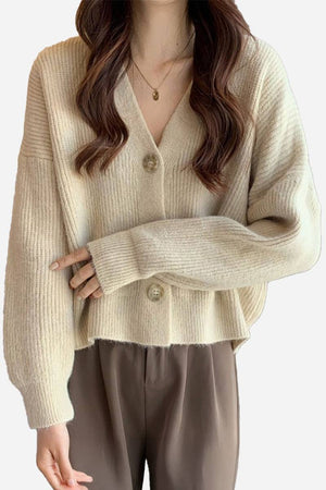 Woman wearing beige casual loose boxy cardigan with V-neck and buttons paired with brown pants