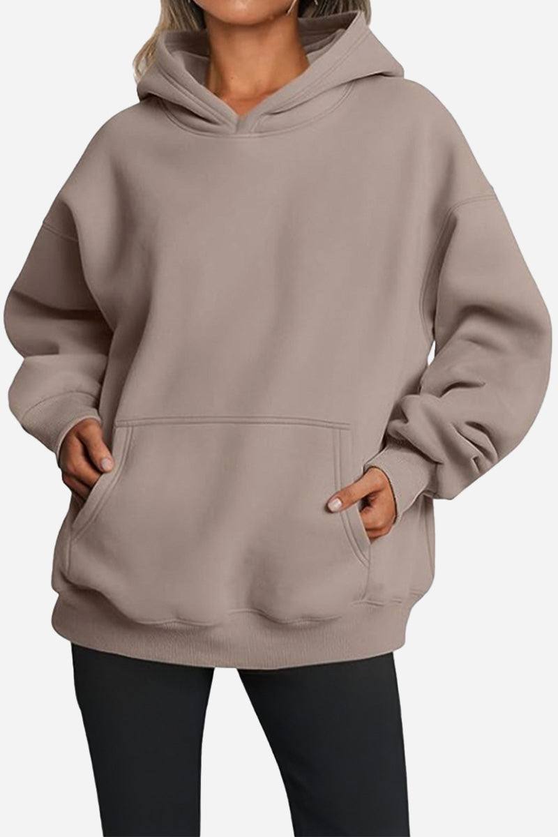 Woman wearing taupe oversized fleece-lined hoodie with front pocket and relaxed fit