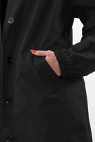 Close-up of black Travel-Smart Waterproof Hooded Windbreaker with elastic cuff and button closure pocket detail