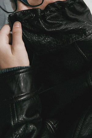 close-up of black sheepskin leather jacket with soft, glossy texture and zipper detail