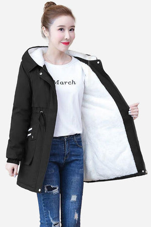 Cityscape Comfort Hooded Windbreaker with plush white fleece lining, black exterior, mid-length fit, and hood, modeled on woman wearing jeans and a white t-shirt.