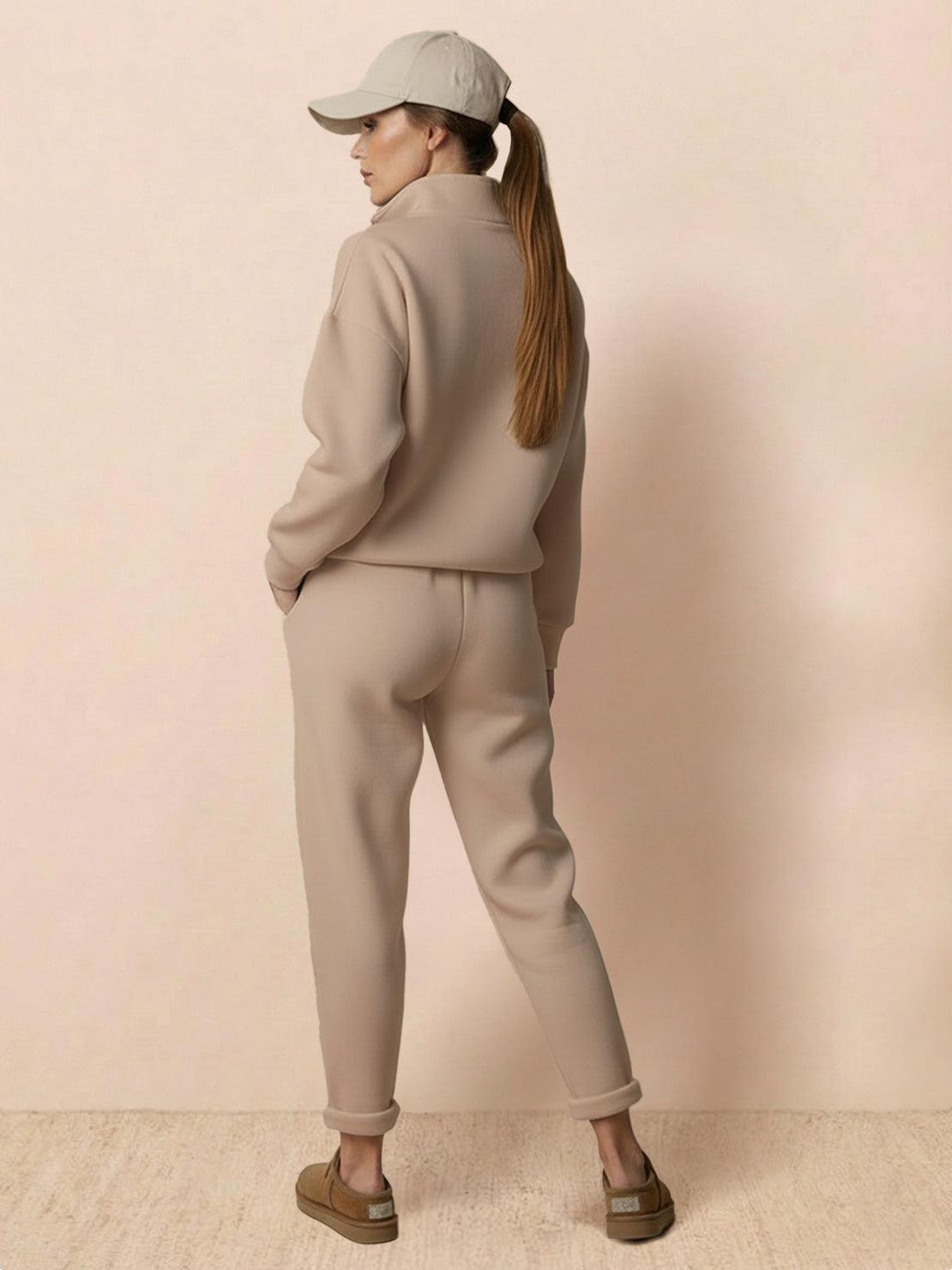 Woman wearing beige Warm & Easy Two-Piece Set with relaxed fit sweatshirt and matching pants, styled with a cap and casual shoes.
