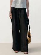 White Tencel-linen pleated wide-leg pants with structured waist and floor-skimming silhouette