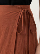 Woman wearing asymmetrical wrap maxi skirt with side tie closure and flowing asymmetric hem in a casual outdoor setting