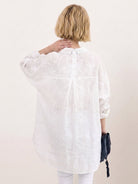 Relaxed oversized linen shirt with button-up front and back-pleat detail on white background