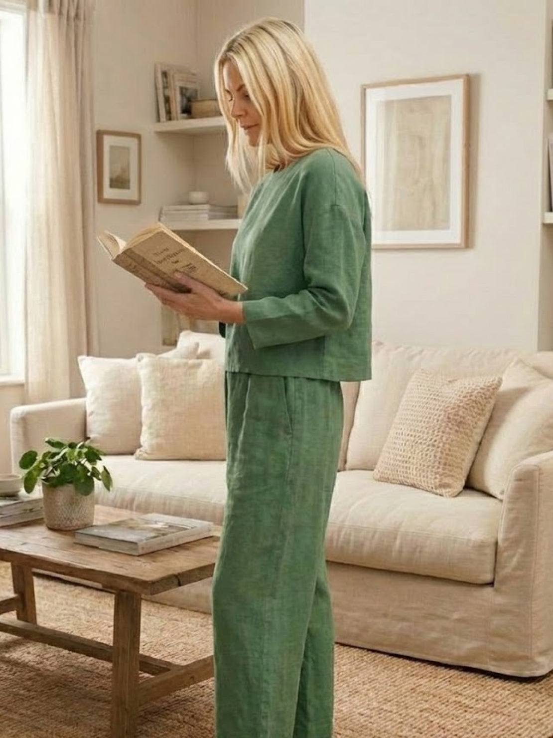 Woman wearing loose solid color two-piece set in green reading book in living room