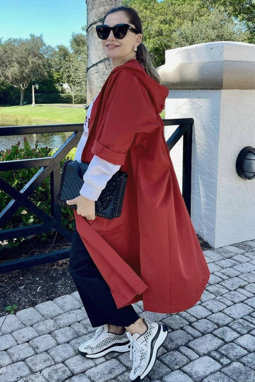 Woman wearing oversized red waterproof windbreaker jacket with hood outdoors