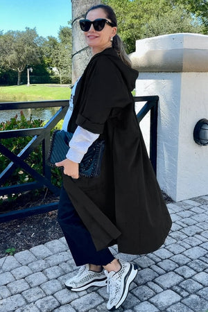 Woman wearing oversized black waterproof design windbreaker jacket with hood outdoors