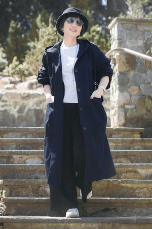 Woman wearing one size fits all oversized waterproof windbreaker jacket with hood and snap-button closure outdoors