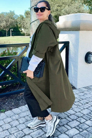 Woman wearing oversized one size fits all waterproof design windbreaker jacket with hood and snap-button closure outdoors
