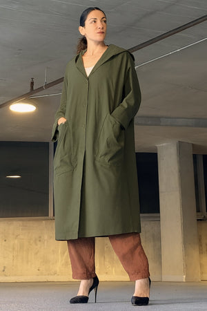 Oversized water-resistant green windbreaker jacket with hood and large pockets, waterproof design.